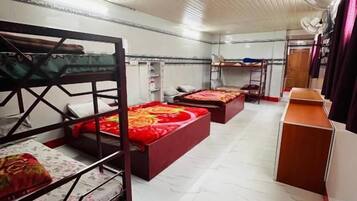 A dormitory room with bunk beds, a desk, and a chair.