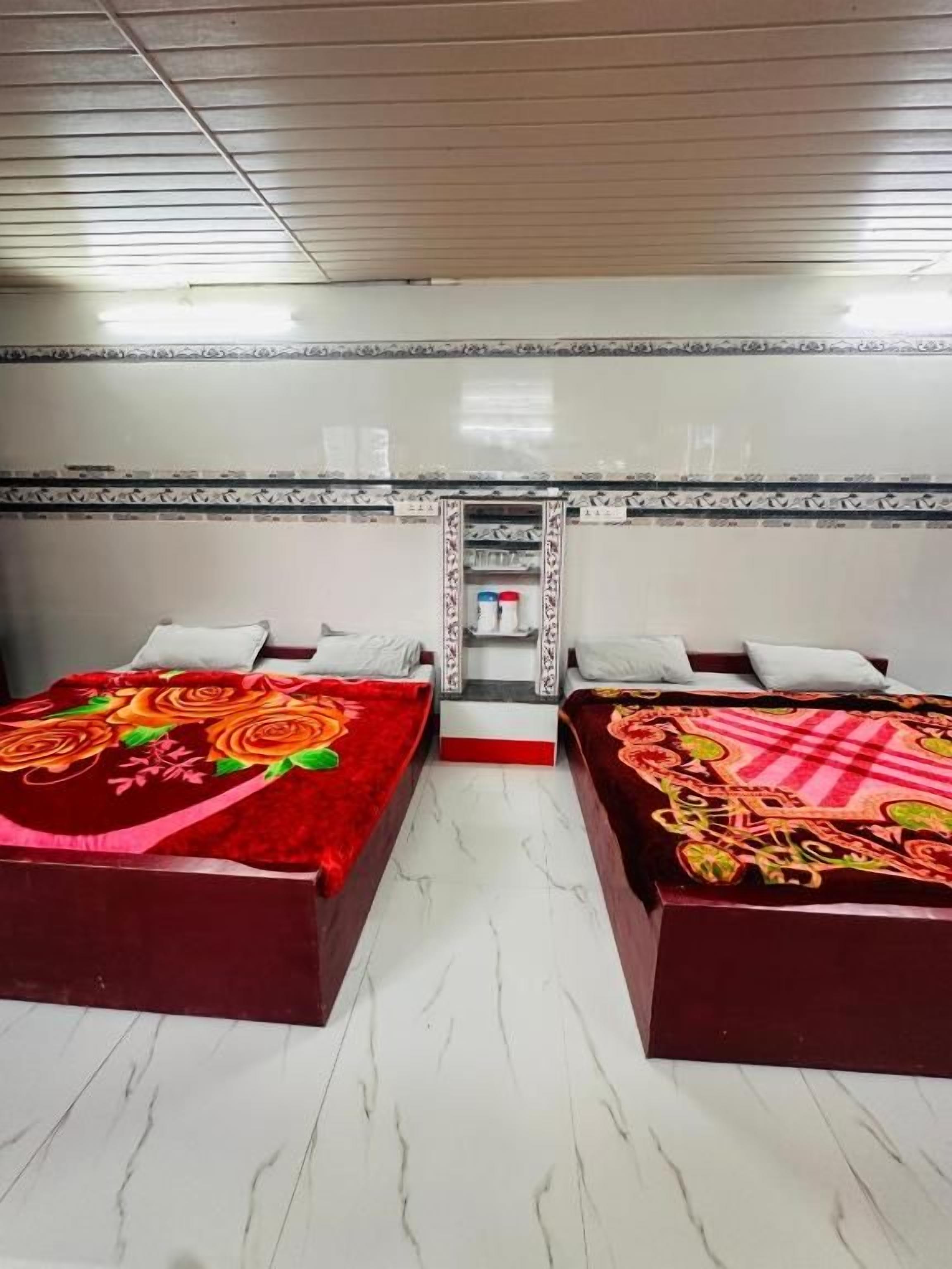 Una habitación de hotel con dos camas, una mesita y un espejo.