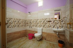 A bathroom with a toilet, sink, and patterned walls. - MSP Amma Cottage (Munnar)