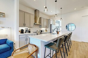 Una cocina moderna con una isla central, taburetes de bar e iluminación colgante.