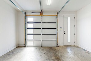 Un garaje con puerta cerrada, piso de concreto y pared blanca.