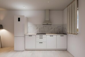 Eine moderne Küche mit Einbaukühlschrank, Herd und Backofen, Marmorfliesenspiegel und einem großen Fenster mit Vorhängen.