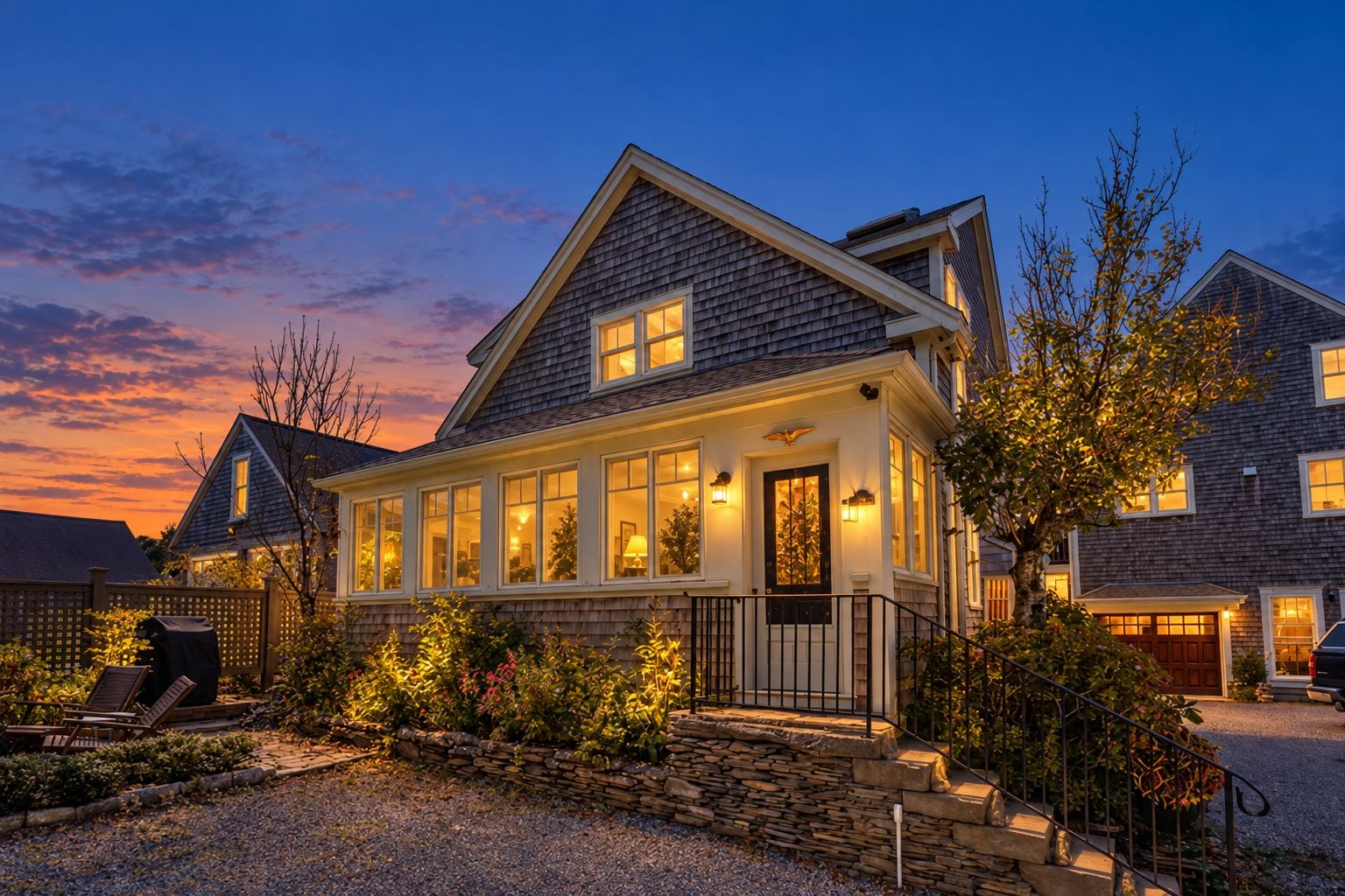 A two-story house with a stone foundation, a front porch, and a well-lit exterior.