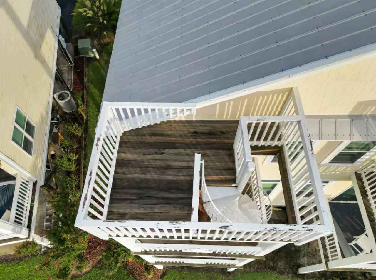 A multi-level residential building with a central staircase, outdoor deck, and surrounding greenery.