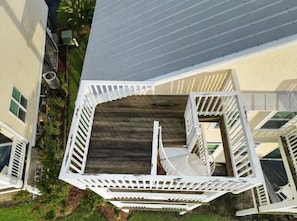 A multi-level residential building with a central staircase, outdoor deck, and surrounding greenery.