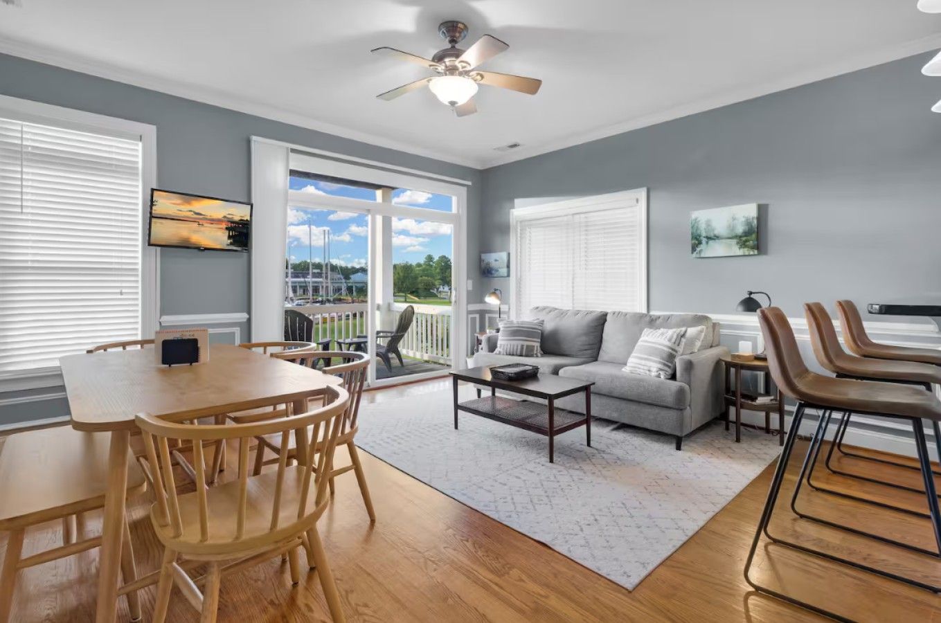 A living room with a grey sofa, a coffee table, and a dining area with a wooden table and chairs.