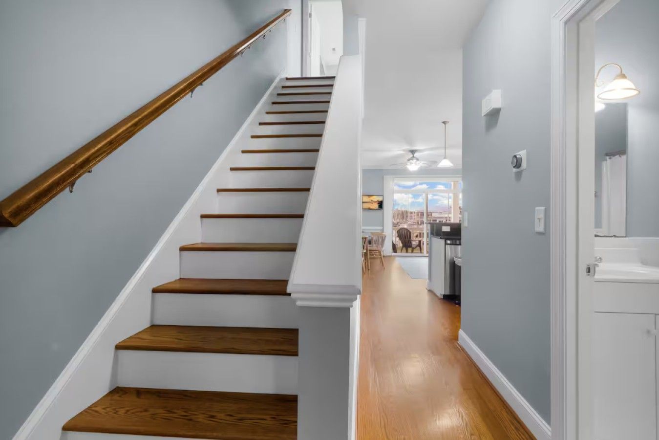 A staircase with wooden steps and a brass handrail leading to a room with a view.