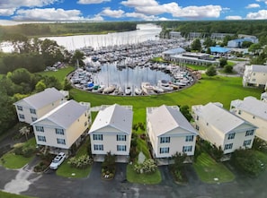 A marina with multiple boats docked, surrounded by residential buildings with a central grassy area. - Marina View Townhome Overlooking Northwest Creek Marina (New Bern)