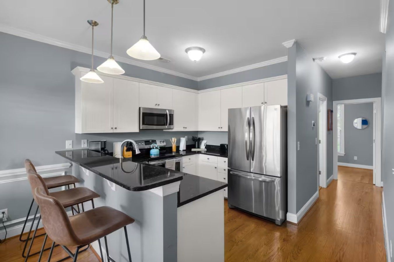 A modern kitchen with white cabinets, stainless steel appliances, and a central island with bar stools.