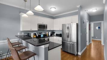 A modern kitchen with white cabinets, stainless steel appliances, and a central island with bar stools.