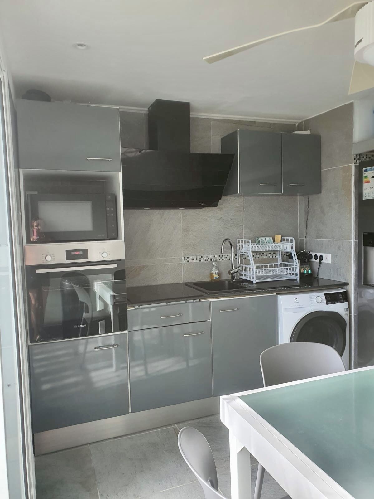 A compact kitchen with a microwave, oven, sink, and a washing machine.