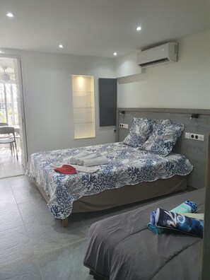Un dormitorio moderno con cama, mesita de noche, silla y ventana.