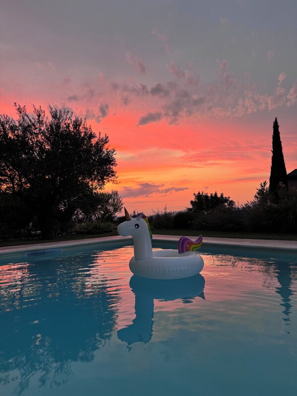 A swimming pool with a unicorn float at sunset.
