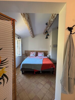 Ein Schlafzimmer mit einem Bett, einem Nachttisch, einer Lampe und einem Fenster.