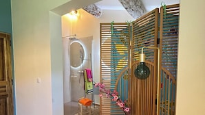A bathroom with a shower, a towel rack, and a decorative glass vase.