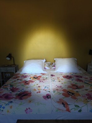 A bed with a floral bedspread, two pillows, and a nightstand with a lamp. - Au Clair Ventoux (Saint-Didier)