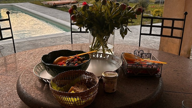 A dining table with a view of a pool and landscape, surrounded by chairs.