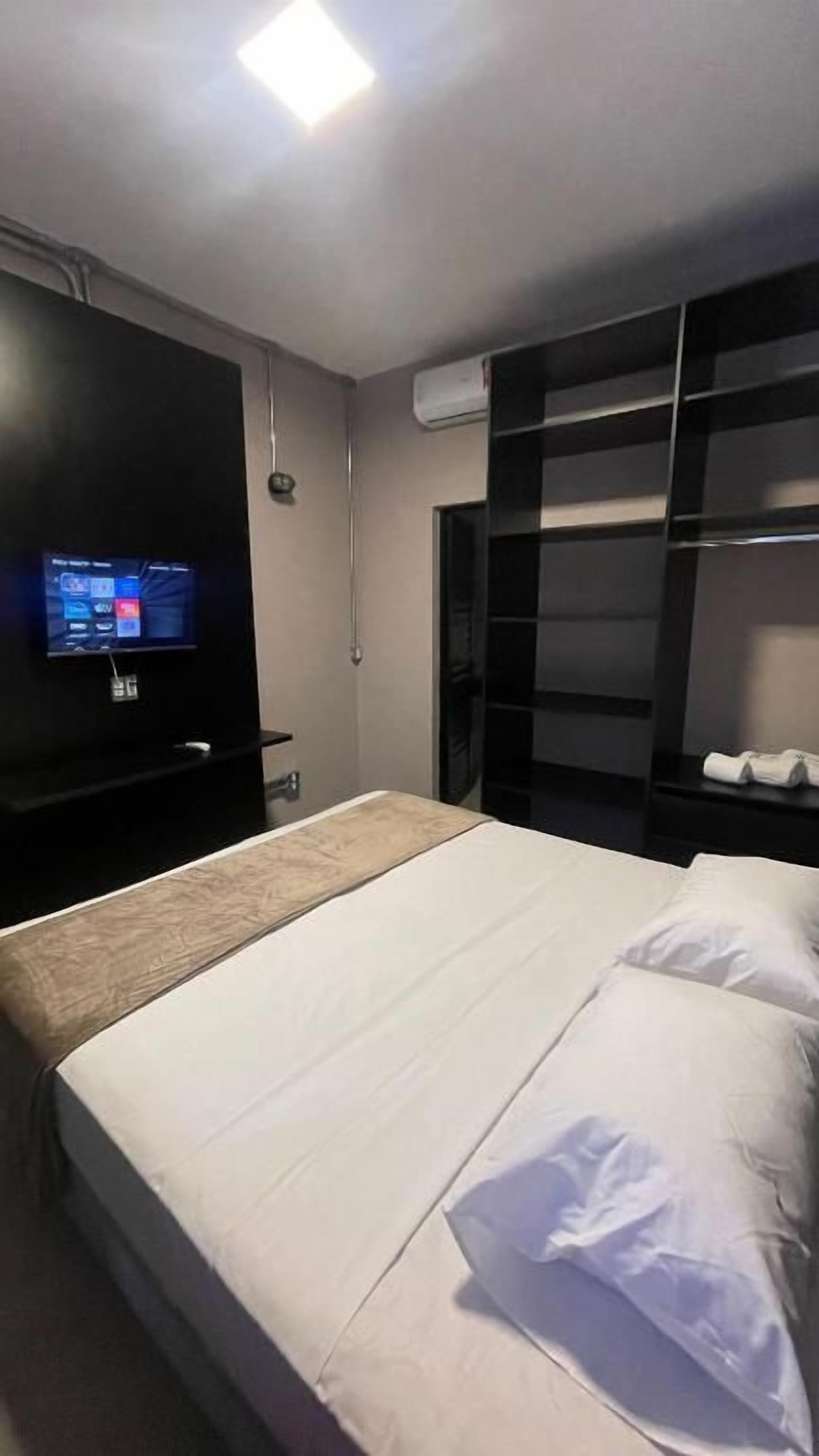 A hotel room with a bed, a TV, and a wardrobe.
