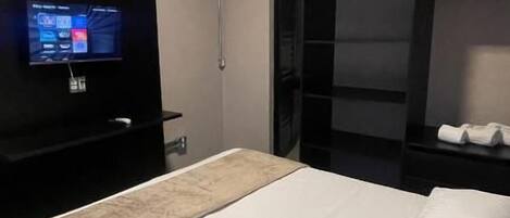 A hotel room with a bed, a TV, and a wardrobe.