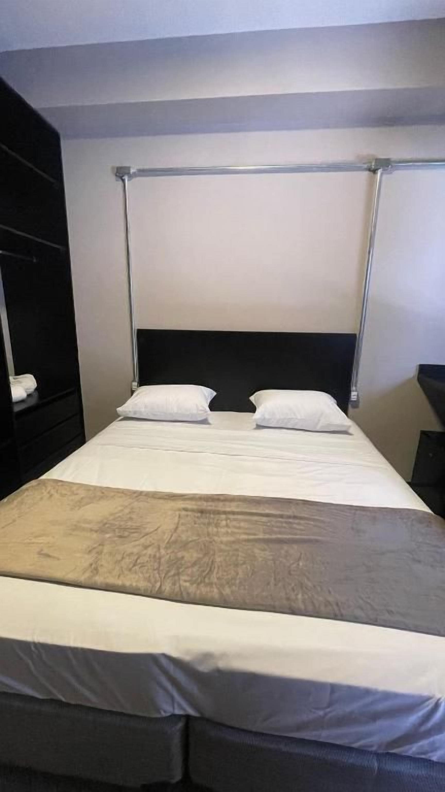 A standard hotel room with a bed, a headboard, and a nightstand.