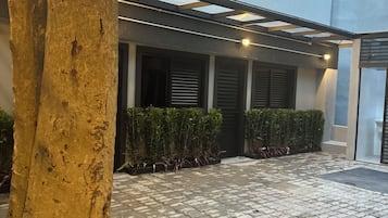 Une cour avec un arbre, un toit en verre et un chemin pavé.