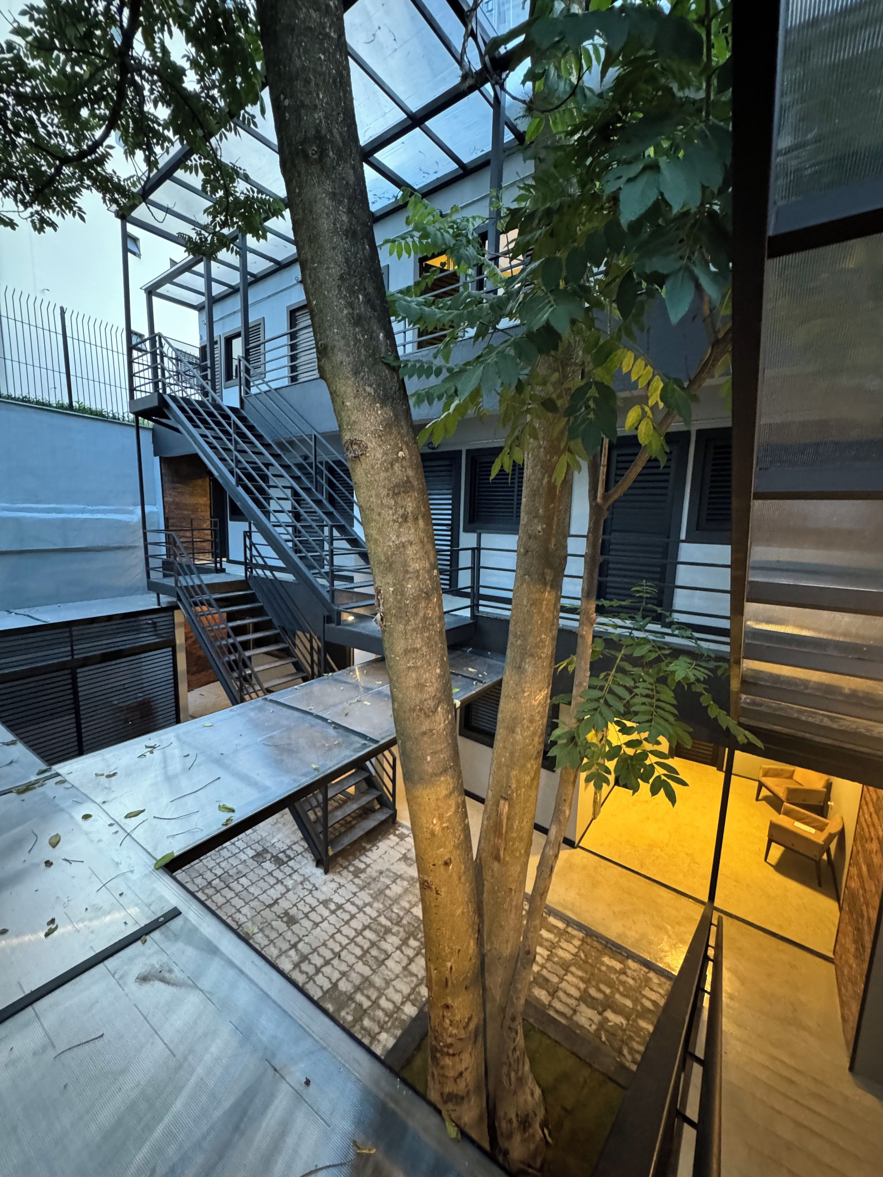 Un bâtiment moderne avec une façade en verre, des escaliers en métal et des arbres.