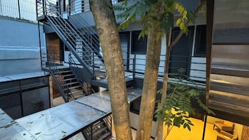 Un bâtiment moderne avec une façade en verre, des escaliers en métal et des arbres.