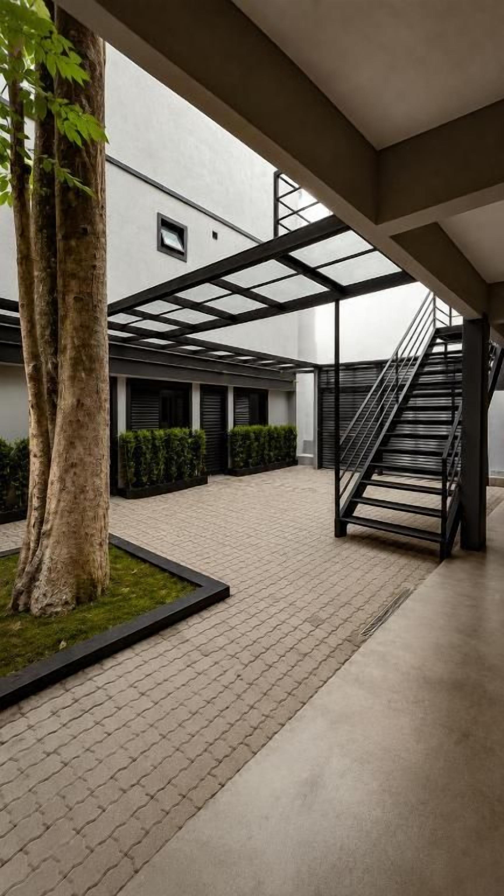 Un patio con una escalera, un árbol y un seto.