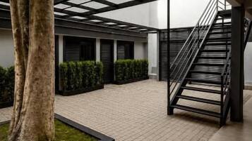 Un patio con una escalera, un árbol y un seto.