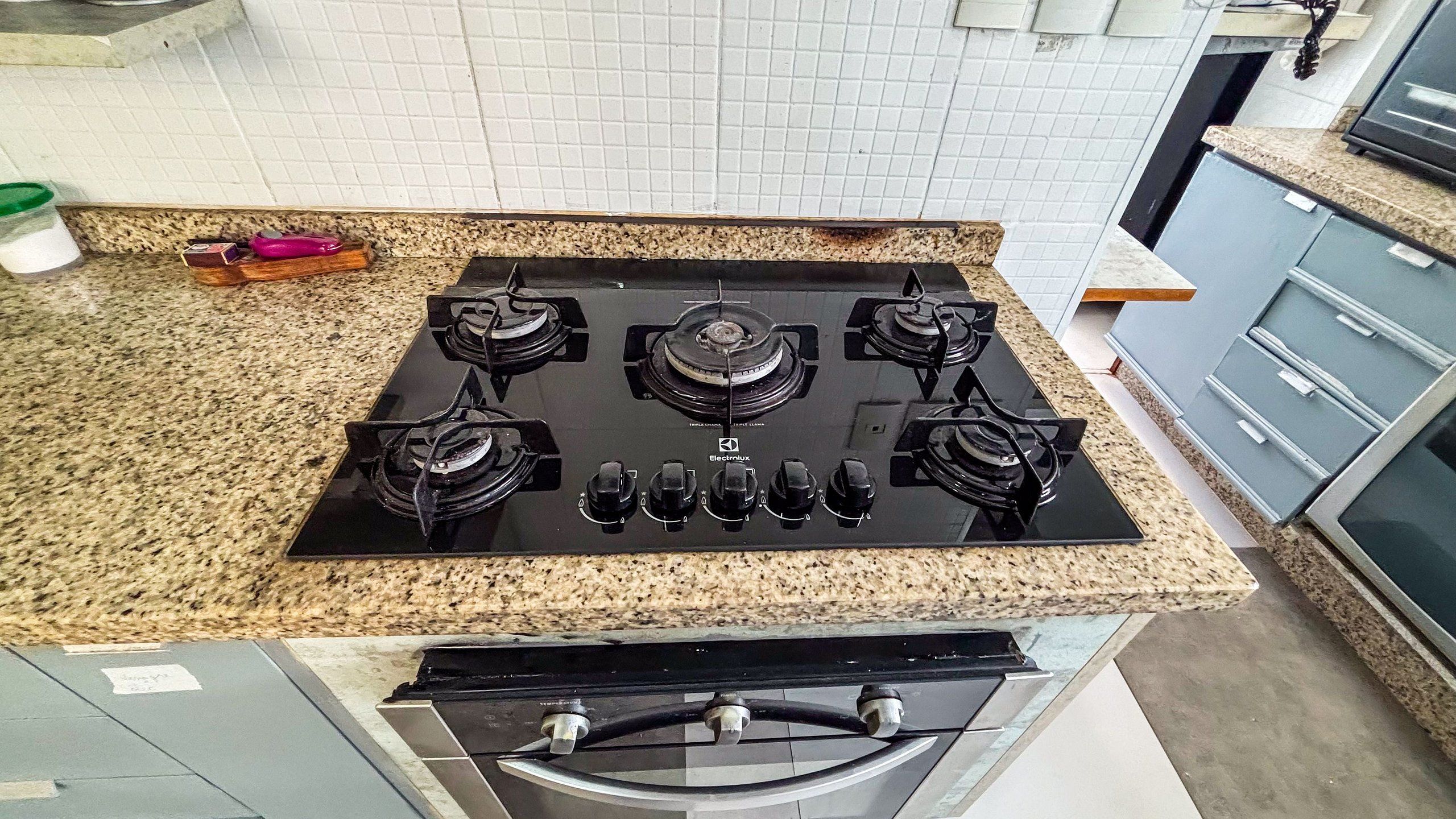 A kitchen with a four-burner gas stove, granite countertop, and stainless steel cabinets.
