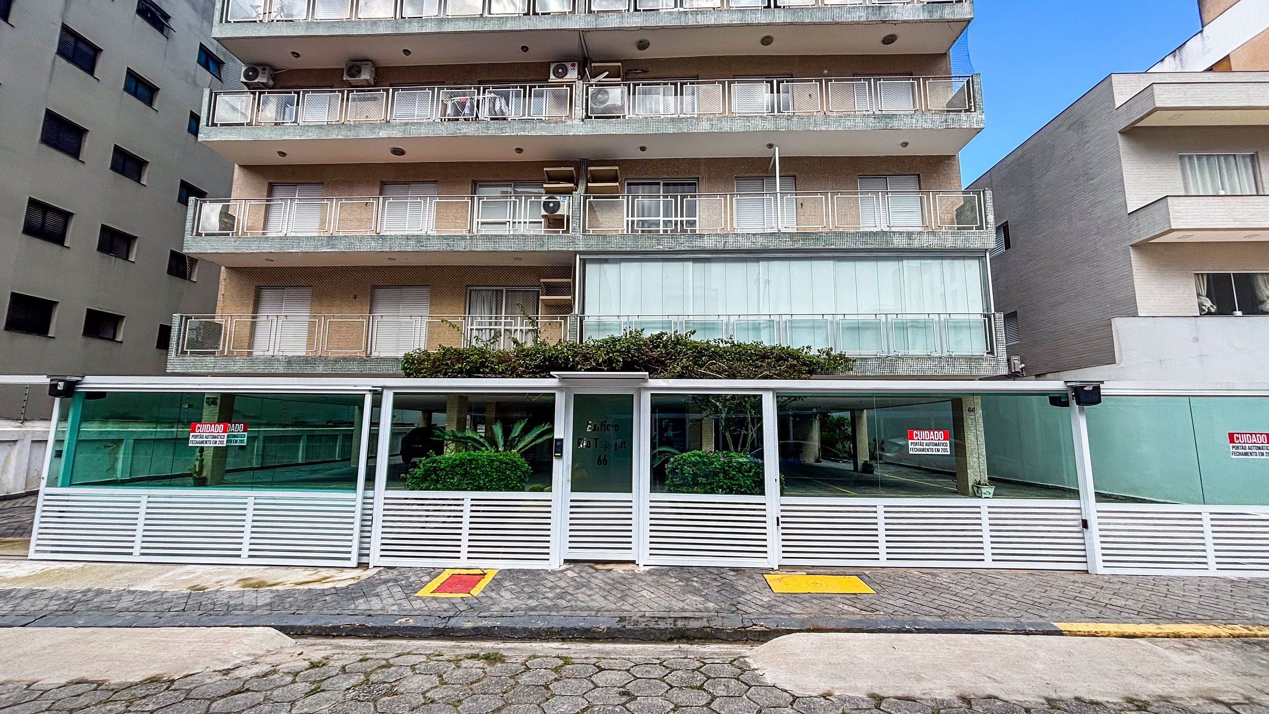 Um edifício com vários andares, varandas, portão e um aviso indicando que está fechado.