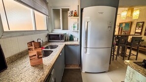 A kitchen with a refrigerator, microwave, sink, and a countertop with a coffee maker and a box labeled 'SUPER HOST.' - SHB Cobertura e Piscina Privativa  (GUARUJÁ)