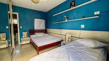 Un dormitorio con dos camas, una pared azul decorativa y un cabecero de madera.