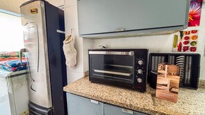 A kitchen with a refrigerator, a toaster oven, and a microwave. - SHB Cobertura e Piscina Privativa  (GUARUJÁ)