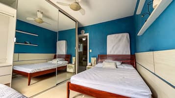 Un dormitorio con dos camas, un espejo, ventiladores de techo y un reloj en la pared.