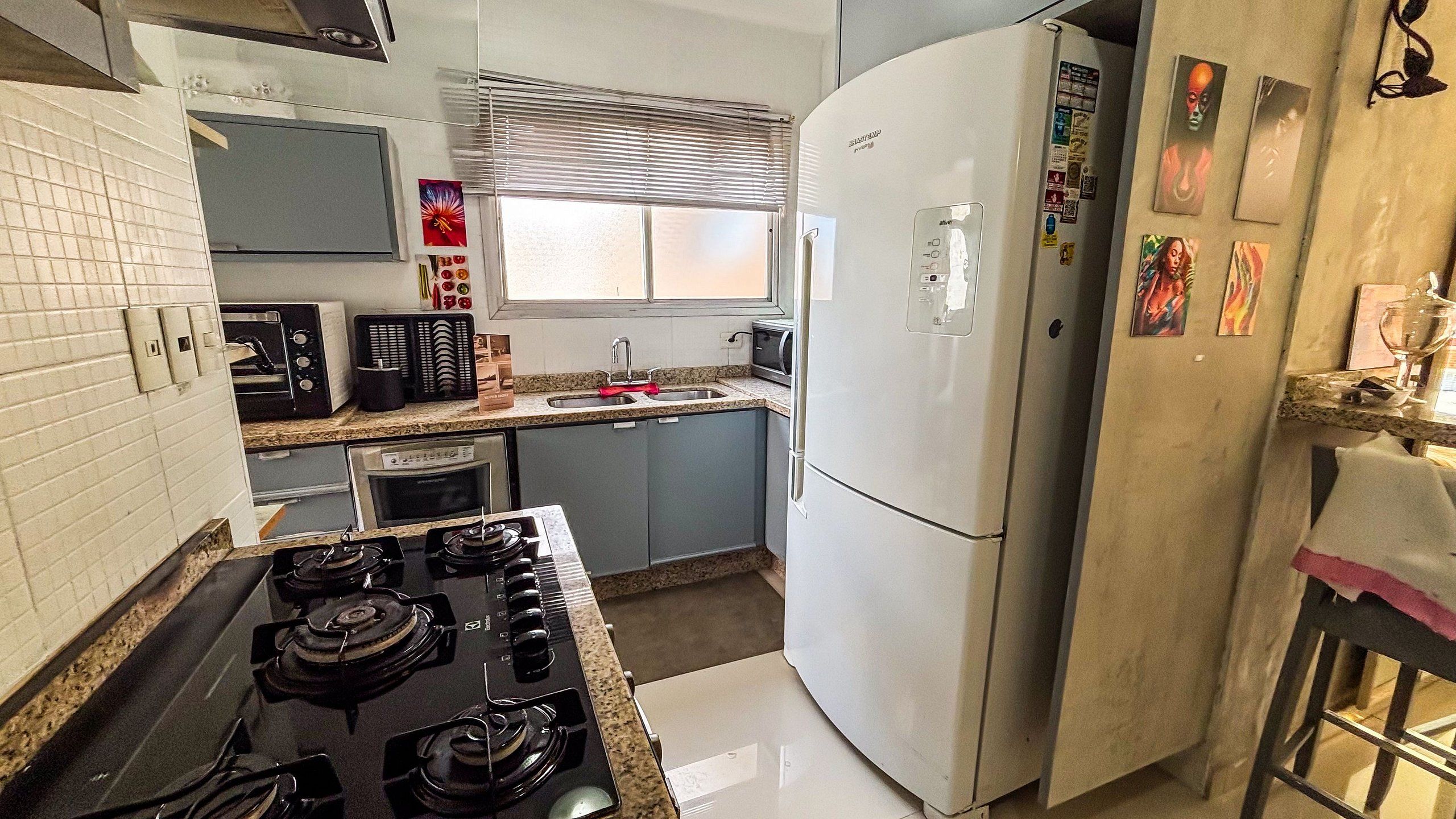 Una cocina con estufa a gas, microondas, lavaplatos y refrigerador.