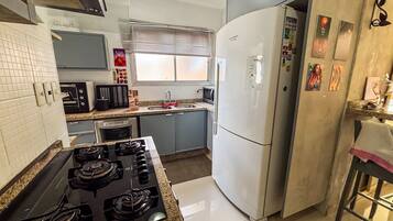 Una cocina con estufa a gas, microondas, lavaplatos y refrigerador.