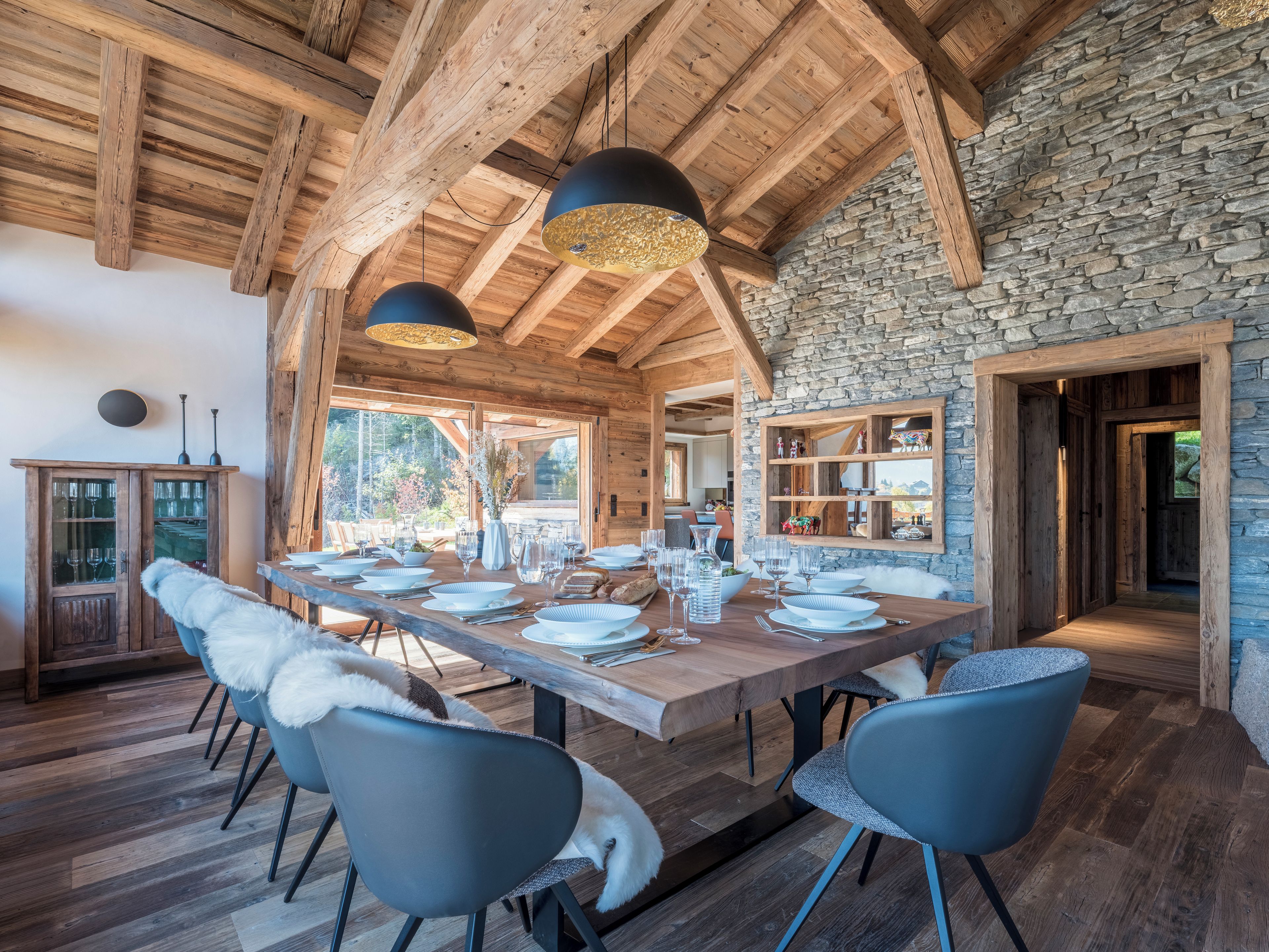 A wooden dining area with a stone wall, a wooden ceiling, and a view of the outdoors.