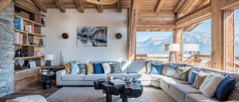Una sala de estar acogedora con chimenea, un conjunto de sofás, una mesa de centro y una estantería.