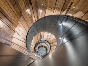 En spiraltrappa med träpanel på insidan och ett metalliskt räcke.