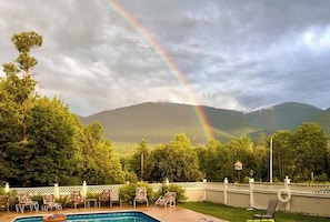 Una piscina amb gandules, una tanca blanca i muntanyes al fons.