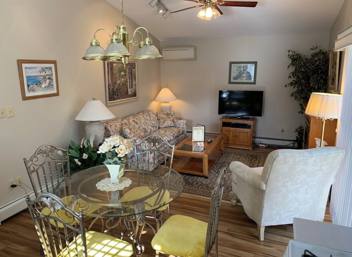 A living room with a sofa, a coffee table, a TV, a lamp, and a ceiling fan.