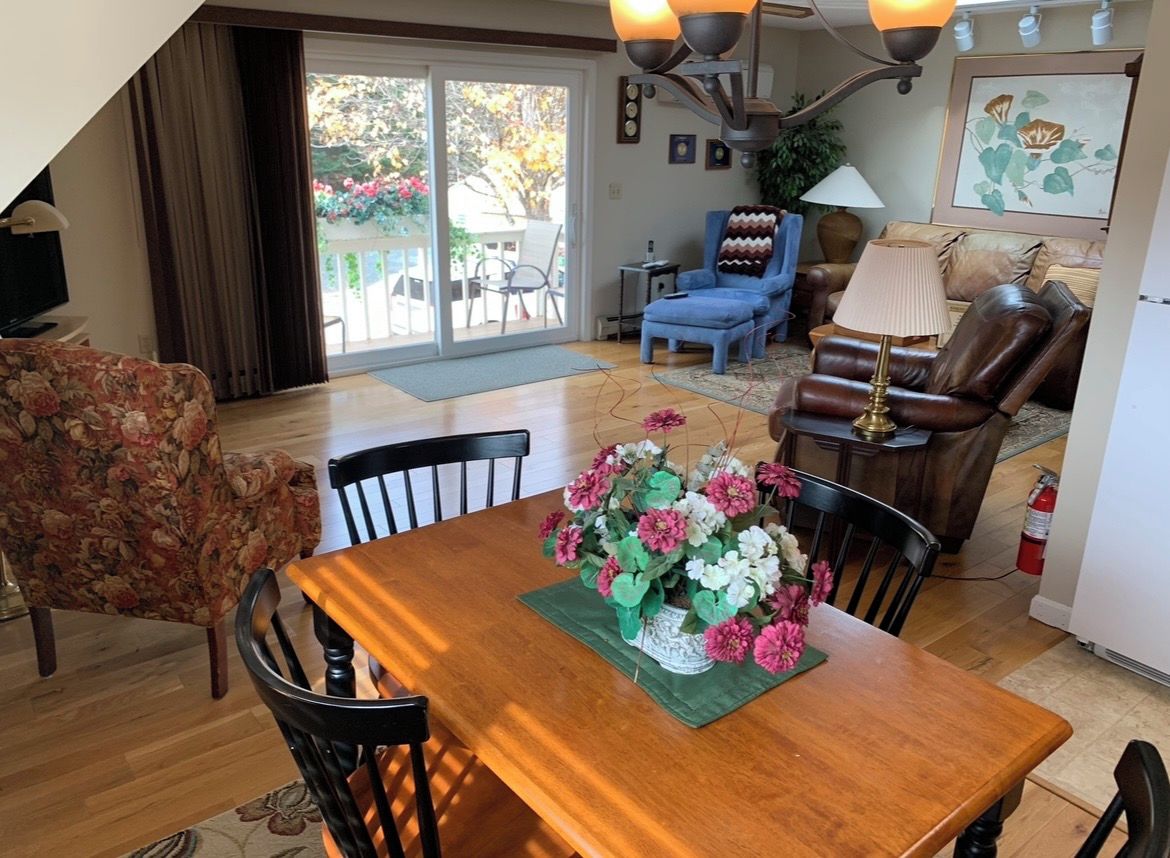 Un coin repas avec une table en bois, des chaises et un arrangement floral en guise de décoration centrale.