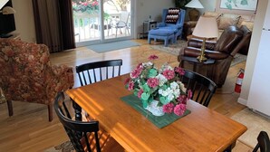 A dining area with a wooden table, chairs, and a floral centerpiece. - Bowman inn Spacious 12-bedroom estate in beautiful Randolph with AC/pool/hottub (Randolph)