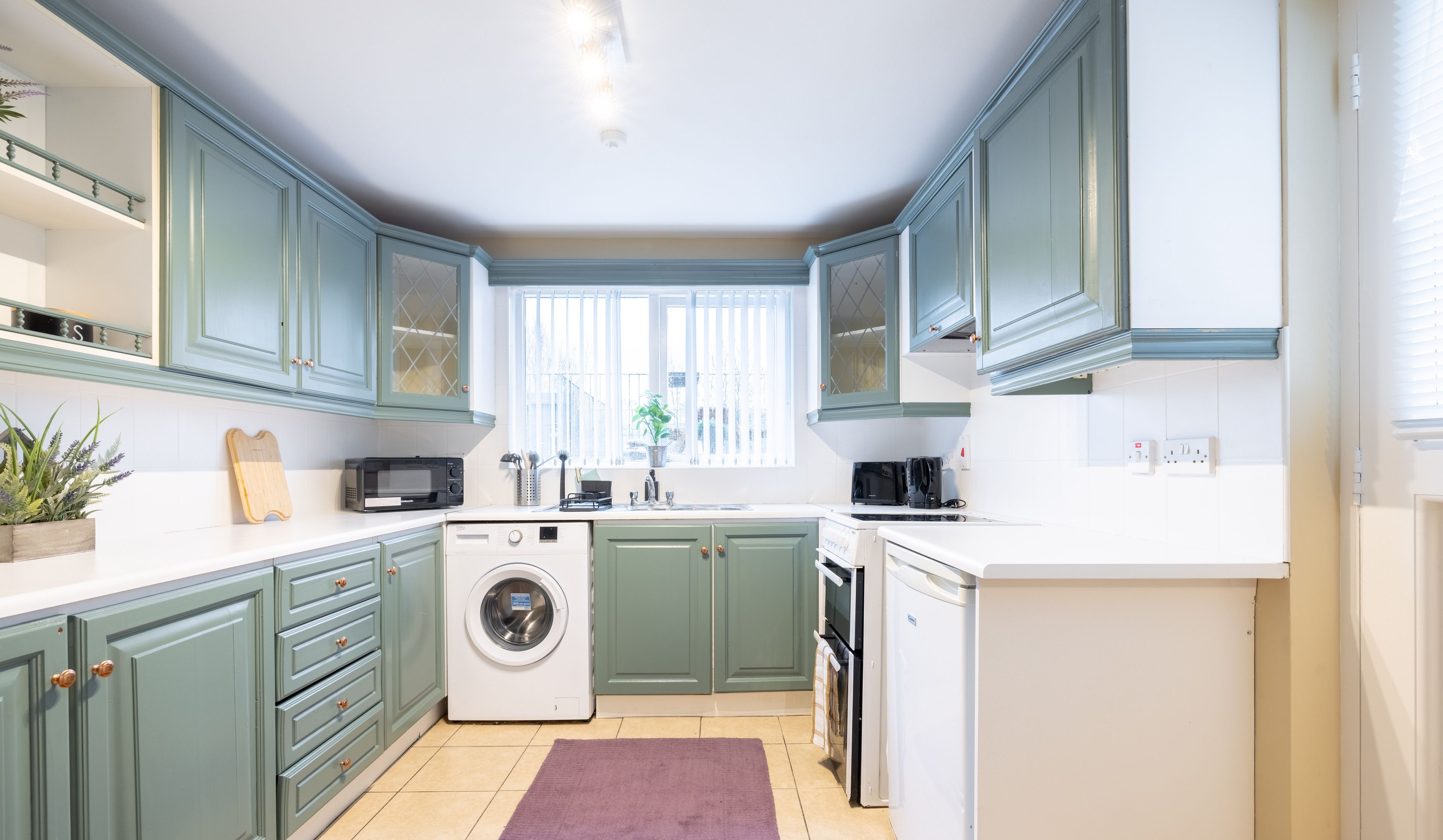 A compact kitchen with a washing machine, microwave, and sink.