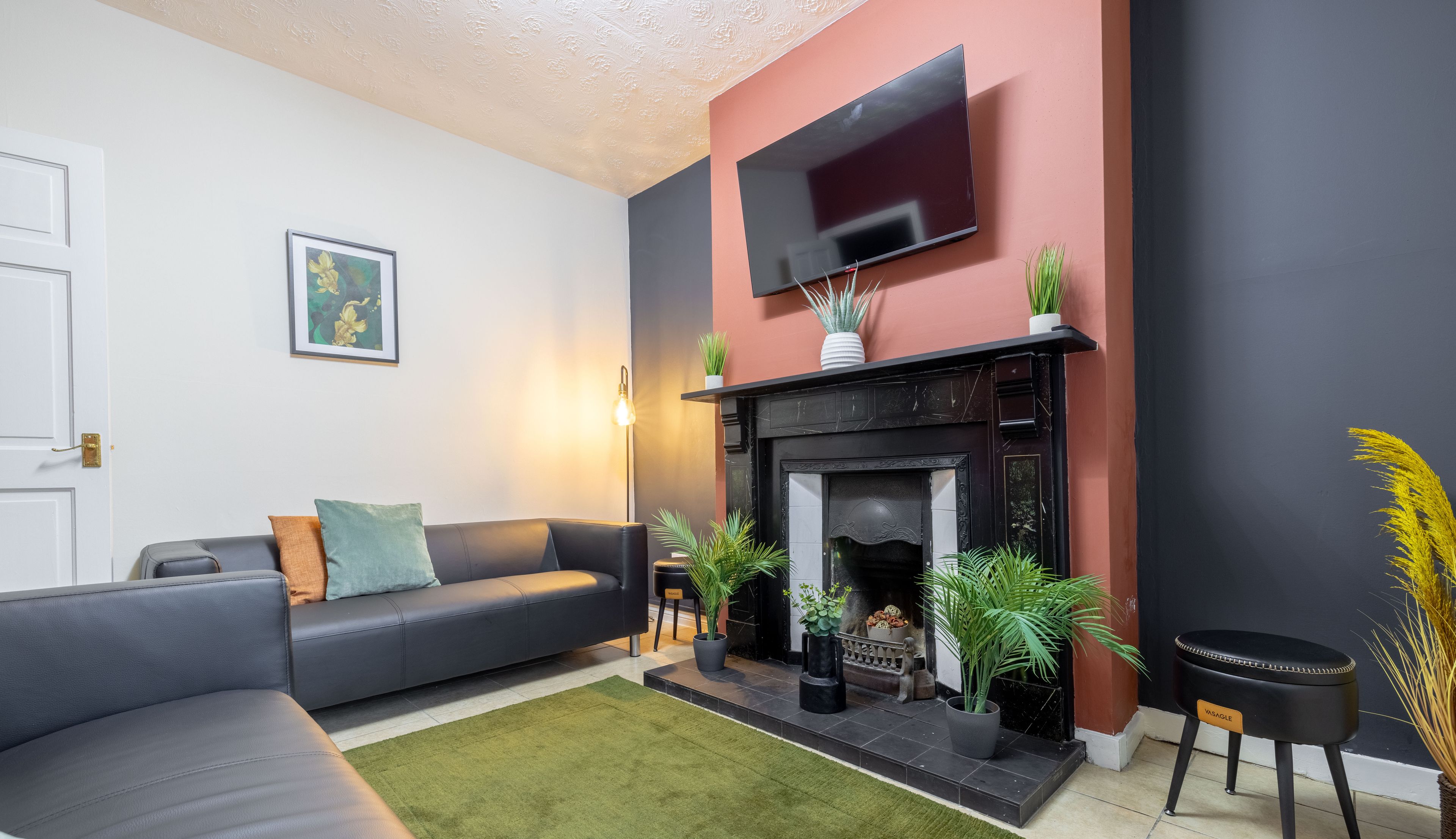 A modern living room with a fireplace, a sofa, and a flat-screen TV mounted on the wall.
