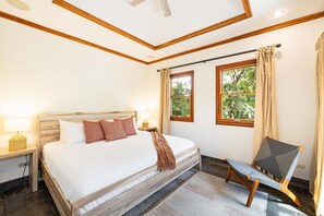 Une chambre à coucher avec un lit, des lampes de chevet, une chaise et des fenêtres.