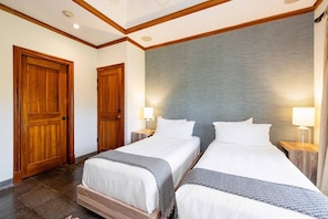 Habitación de hotel con dos camas, puertas de madera y una pared con textura.