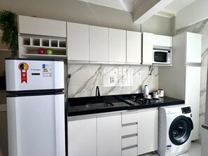 A compact kitchen with a refrigerator, microwave, sink, and washing machine. - 105 · 105 AP 2 Bedrooms Practical and Functional (Belém)