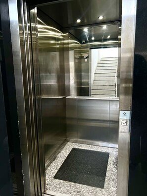 An empty elevator with metallic walls, a small window, and a control panel. - 105 · 105 AP 2 Bedrooms Practical and Functional (Belém)